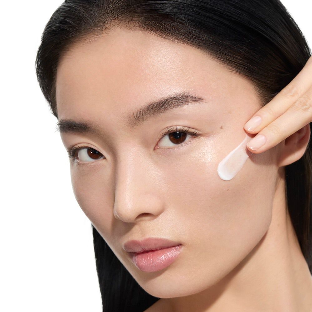 Wen, YSL Beauty-model met een lichte huid, brengt YSL Beauty Pure Shots Youth Reload Cream aan op haar wang.