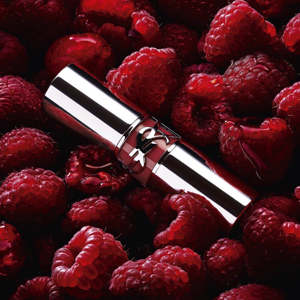 YSL LOVESHINE Berry Crush lipstick, zilveren huls met berry-kleurig YSL-logo, omringd door verse frambozen.
