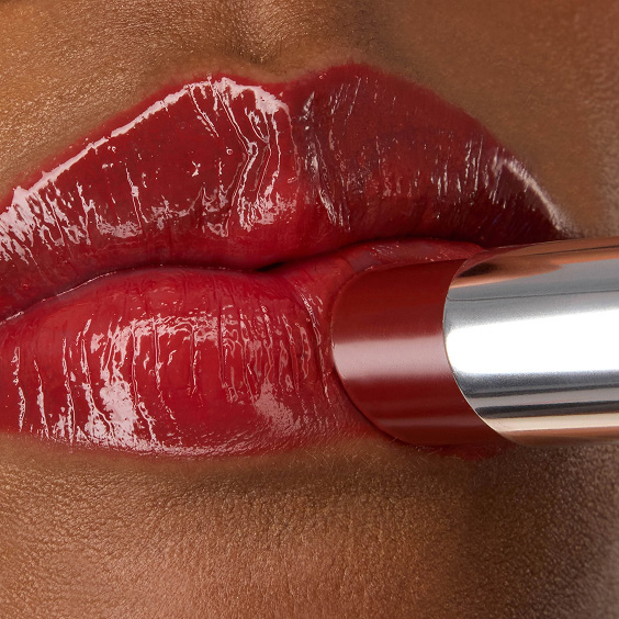 Close-up van de YSL LOVESHINE Lipstick in de kleur Berry Crush, tint 219, die wordt aangebracht op de glanzende, levendige rode lippen van model Zahara.