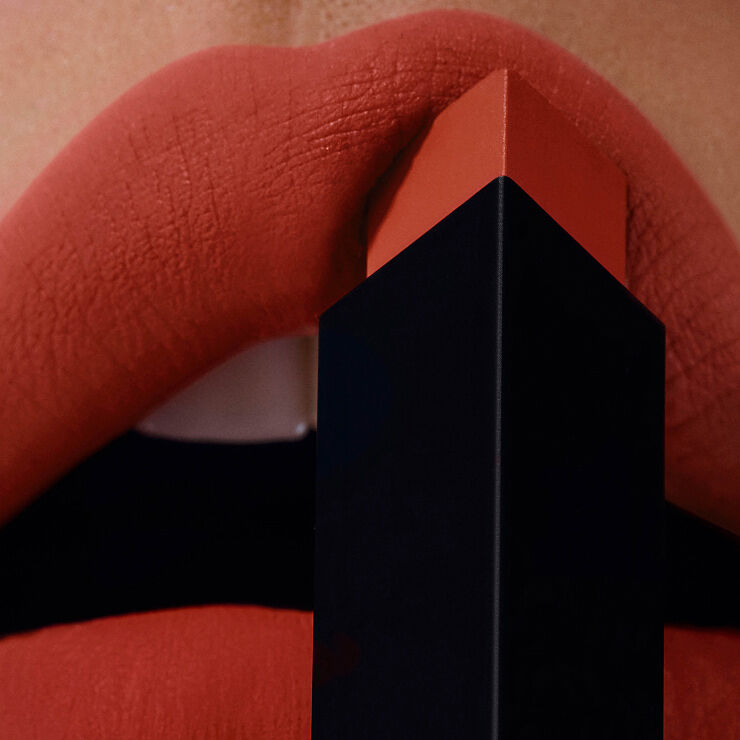 Zwart-gouden YSL huls met Cassandre-logo tegen gouden achtergrond.