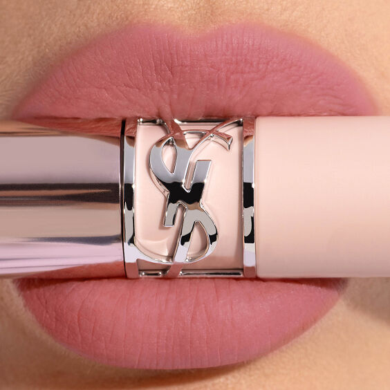 Close-up lips wearing YSL LOVENUDE LIP BLUSHER in Shade 44 with a pale pink YSL lipstick tube and silver Cassandre ring.