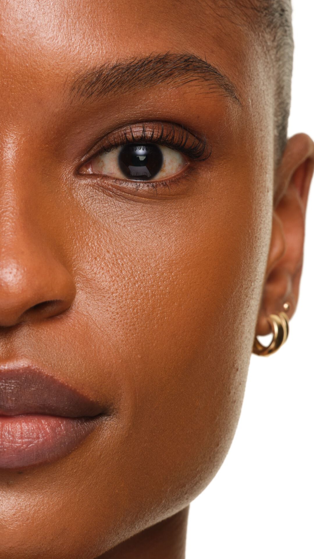 Stralende finish van YSL SKIN AFFAIR FOUNDATION op donkere huid. Extreme zoom toont een gladde, porieloze en luminescente textuur.