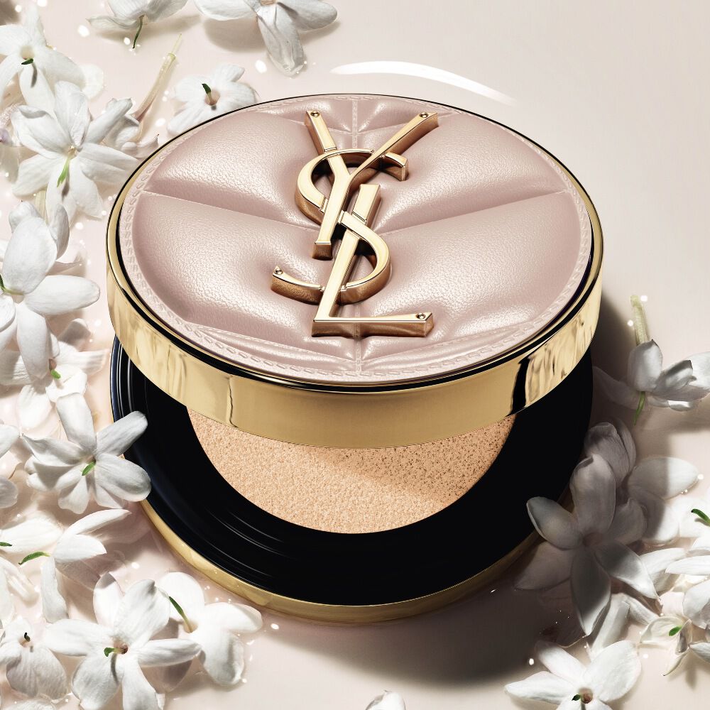 Close-up van YSL SKIN AFFAIR SOFT GLOW CUSHION in een poel van vloeibare foundation en jasmijnbloemen. Stralende, sensoriële finish.